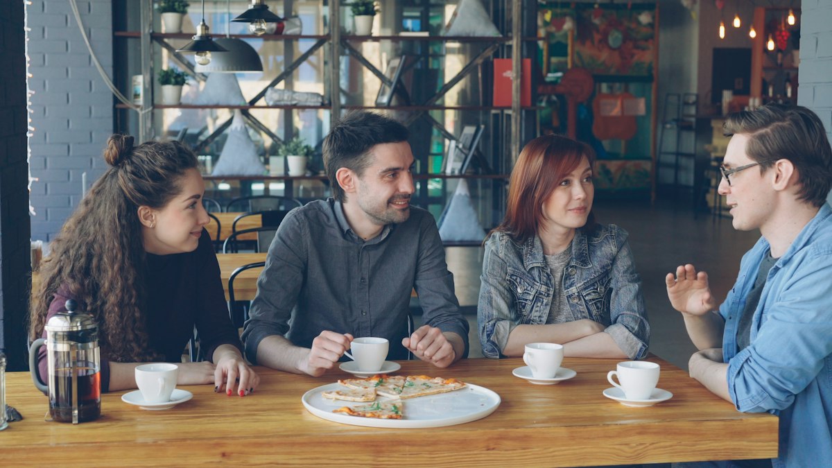 Friends talking over coffee and food at a café table